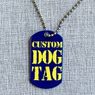 A dark blue military dog tag with yellow text that reads, "custom Dog Tag". The tag is pictured with a ball chain running through a hole in the top of the tag. This dog tag is shown on a gray fabric background. 
