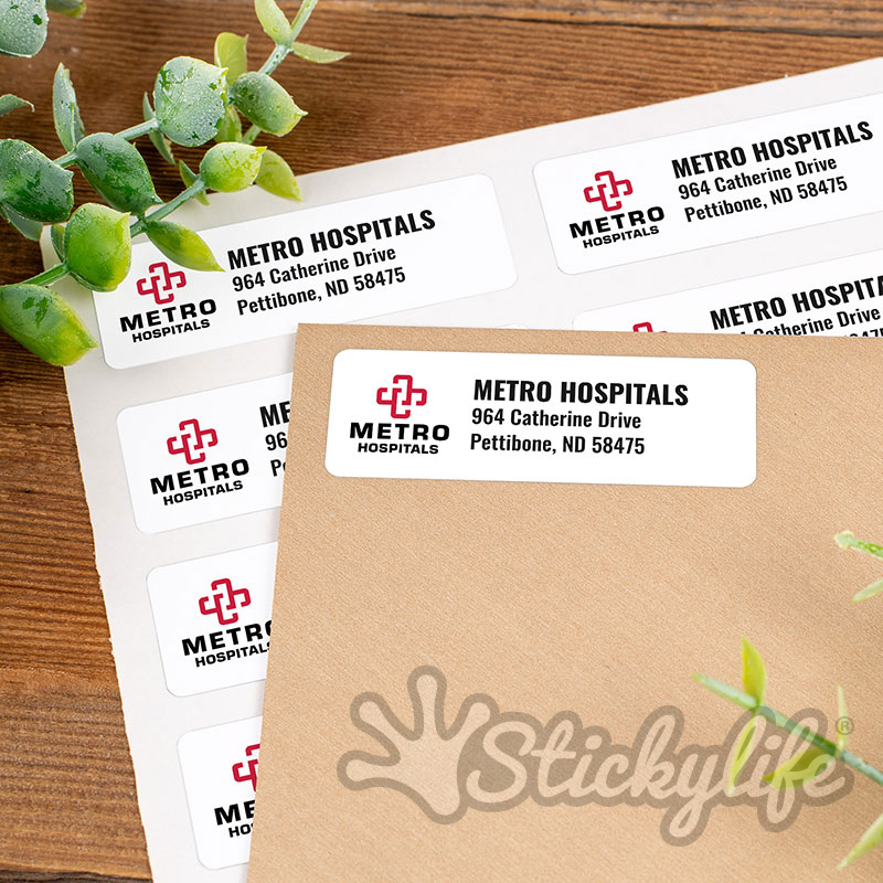 A sheet of custom return address labels with a logo and address, next to a kraft envelope with one label applied.