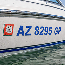 Boat registration numbers decal applied to white motorboat hull
