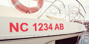 A boat docked at a boat yard with their state required boat registration numbers applied to the bow. 