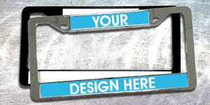 One chrome and one black plastic license plate frame stacked on top of each other placed on top of a brushed metal surface. 