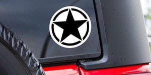 A circle window sticker with a black star printed in the middle installed on the back of a jeeps window next to the spare tire. 